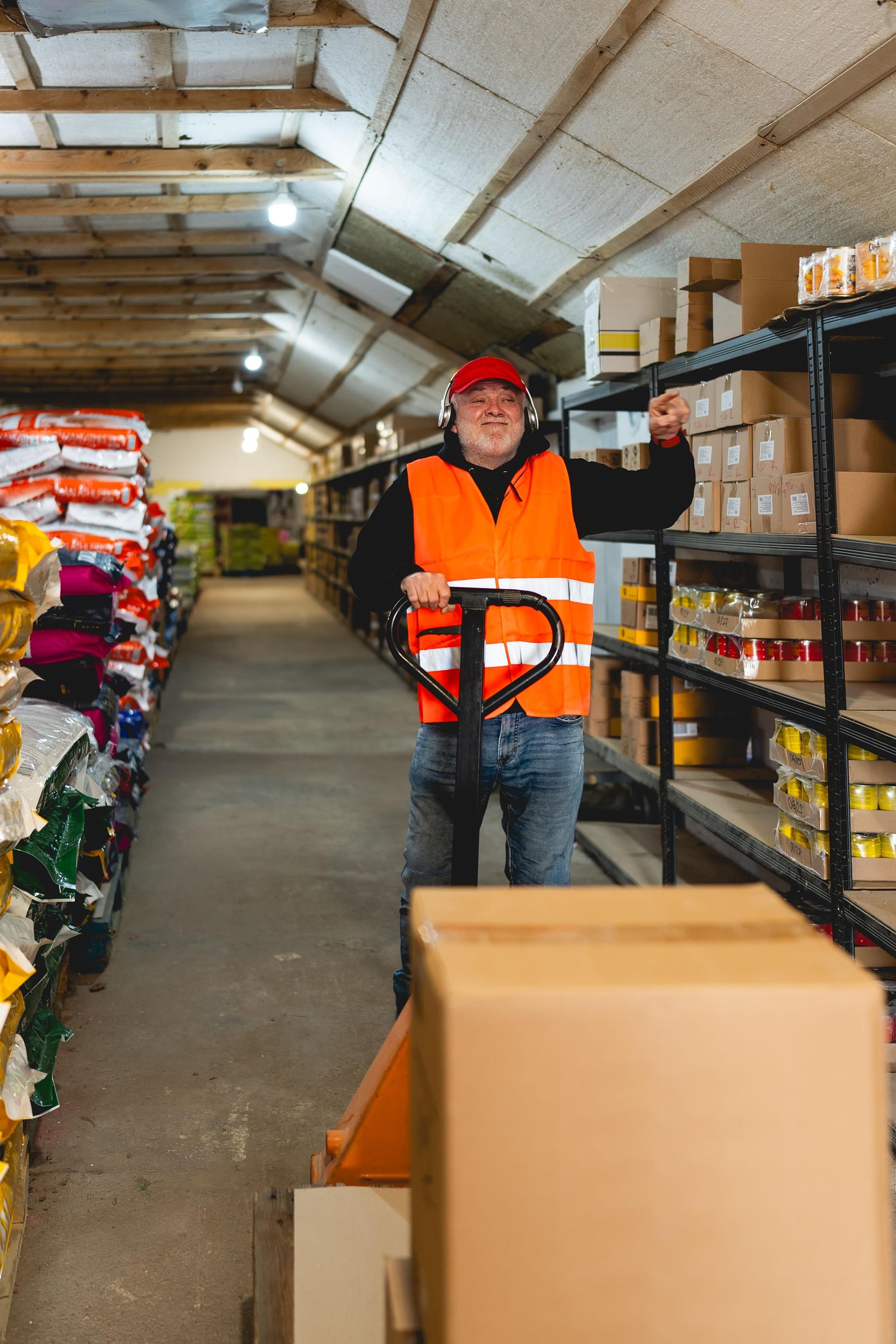 An older worker in a pet food warehouse prepares deliveries of goods for pet stores.